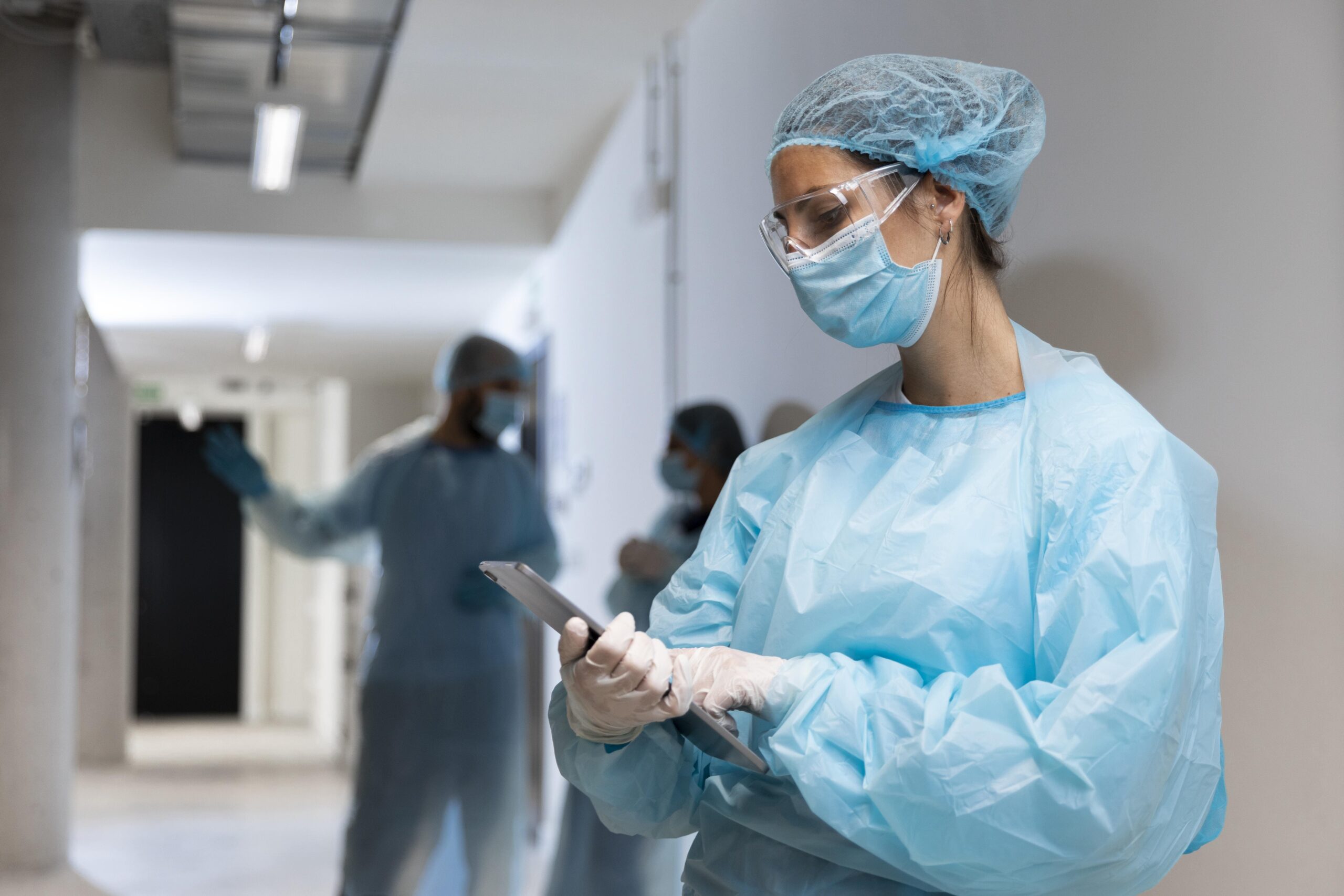 médica usando uma roupa de proteção e olhando para um tablet